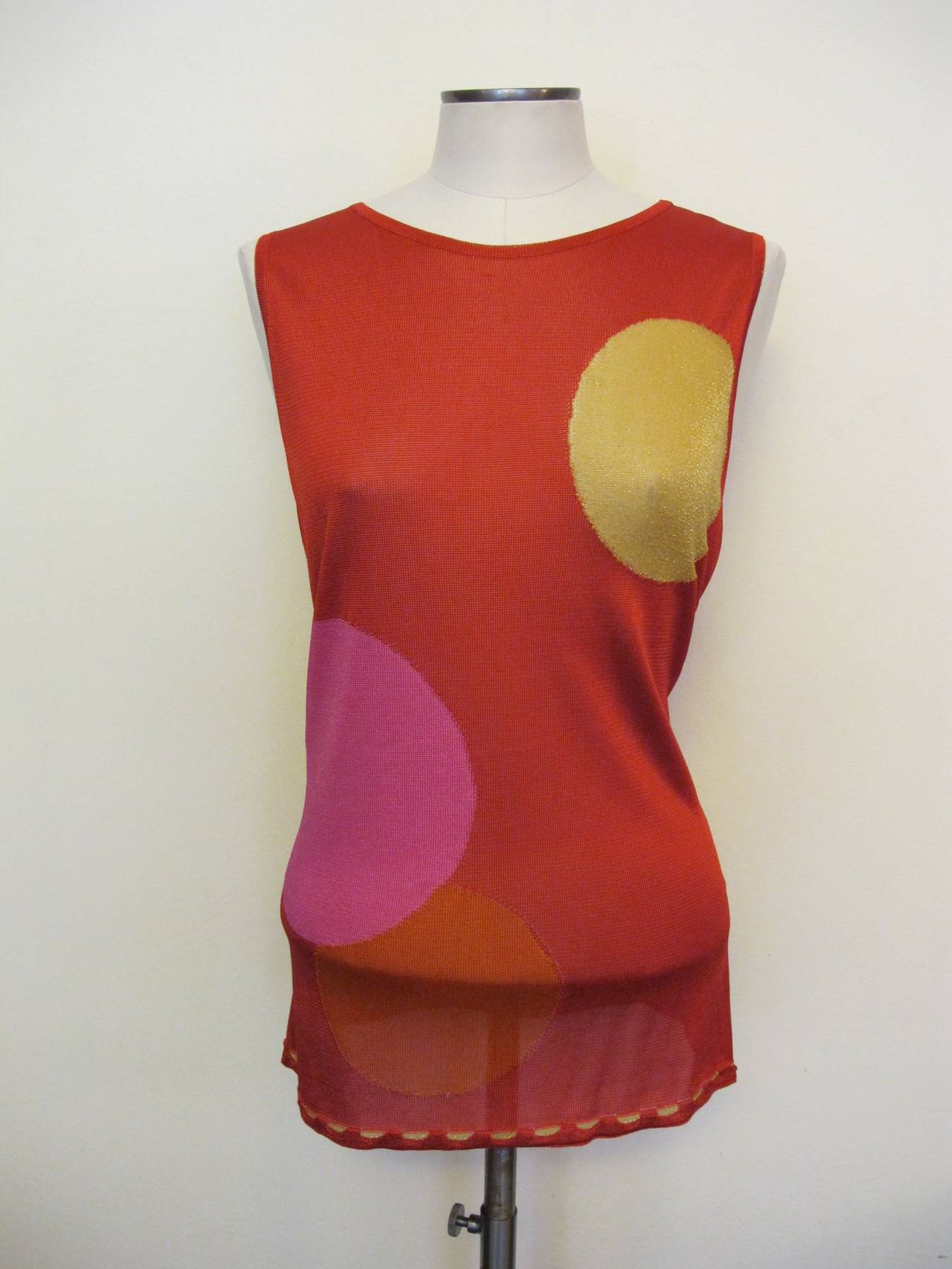 Silky viscose rayon and polyester knit tank with jewel neckline that is trimmed with a gold thread interior band as are the interior arm holes. The silky weave is a warm red with three spheres in shades of pink, orange and gold with shimmery gold