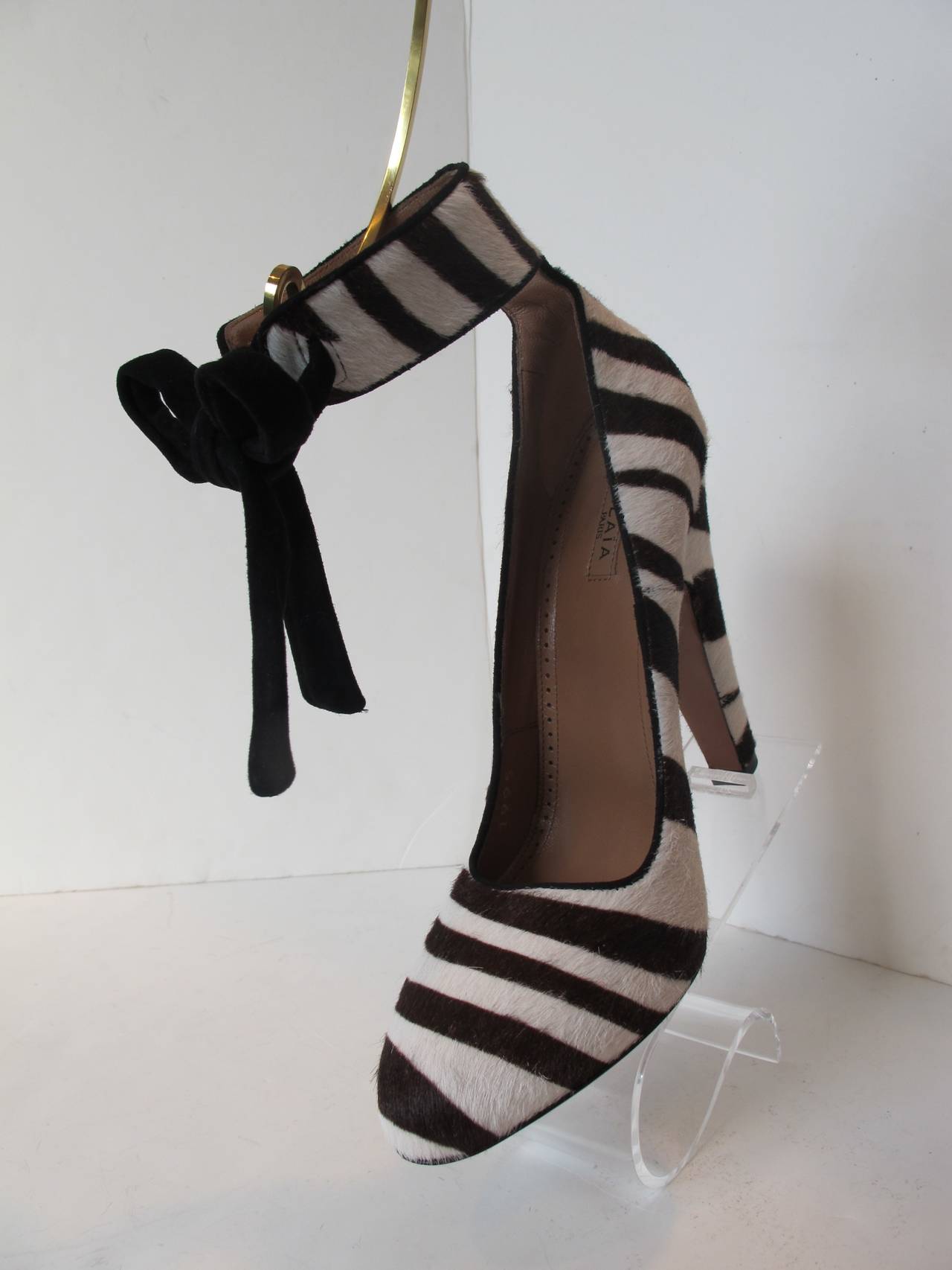 Impressive Alaia Zebra Shoes with Black Stripes. There is an ankle strap which ties with a black suede bow. Heel height is 5.125 inches. The design is 