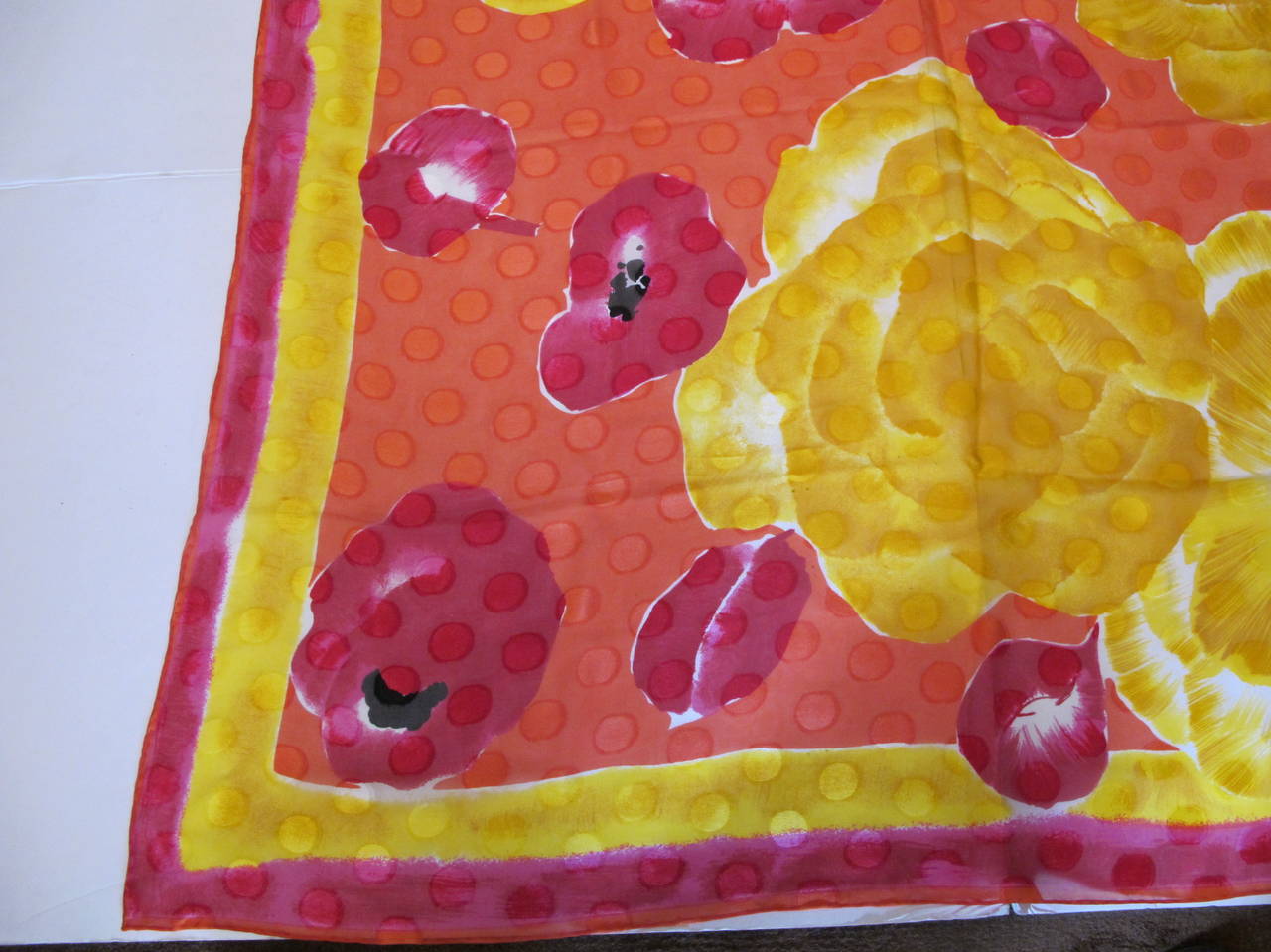 Flowers are embedded in a sea of polka dots. Bright orange, yellow, golden, red, magenta, black and white hand rolled hem scarf. It was owned by a Hillsborough, California Grande Dame and donated to Helpers. This scarf brings joy to the soul.