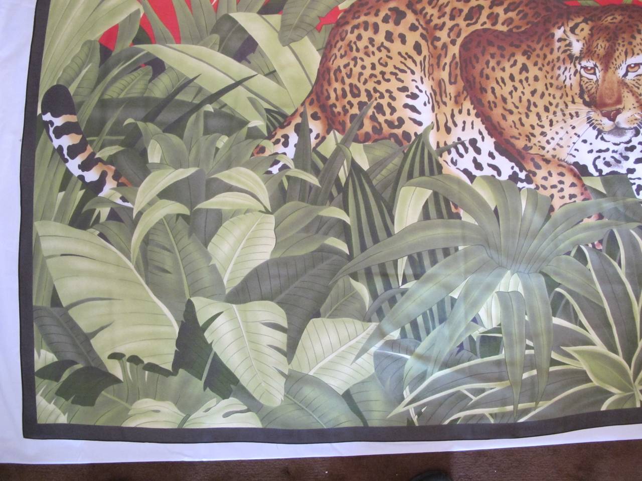 Fabulous jungle leopard Pareo which serves as a shawl or wrap around. The exquisite Leopard exudes a contented counterunce in the setting of exotic green leaves and red background. Hand-rolled hem.