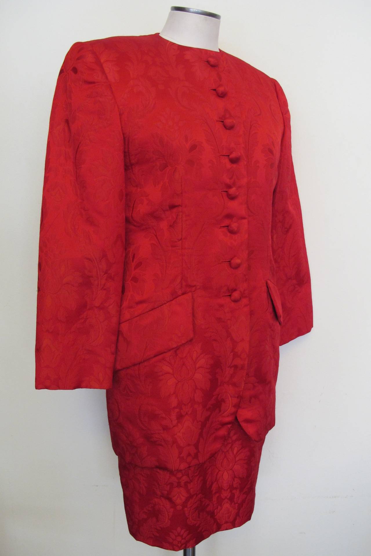 Carolyne Roehm created a stunning red ensemble. The jacket is a rich red brocade which has a tulip shape. It is enriched by eight covered buttons and 2 pockets. The red brocade is exquisite and the top of the dress is created with beautiful heavy