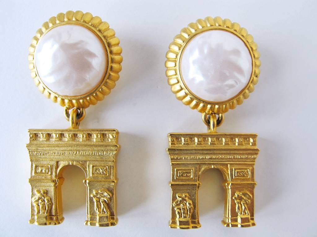 These stunning vintage 1980's Karl Lagerfeld gold-tone and faux pearl pierced earrings have the fabulously detailed Arc de Triomphe dangling from them. They are in excellent condition and are signed. The width of each earring is .75 inches and the