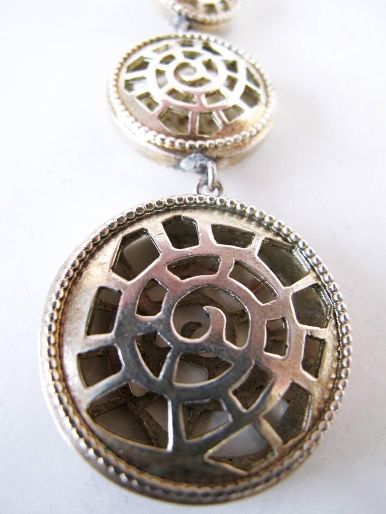 These 1980's silver-toned shoulder duster earrings signed Karl Lagerfeld make a striking statement with the four discs which face and are graduated sizes. The effect on each earring has a shell cut out design.

Length: 4