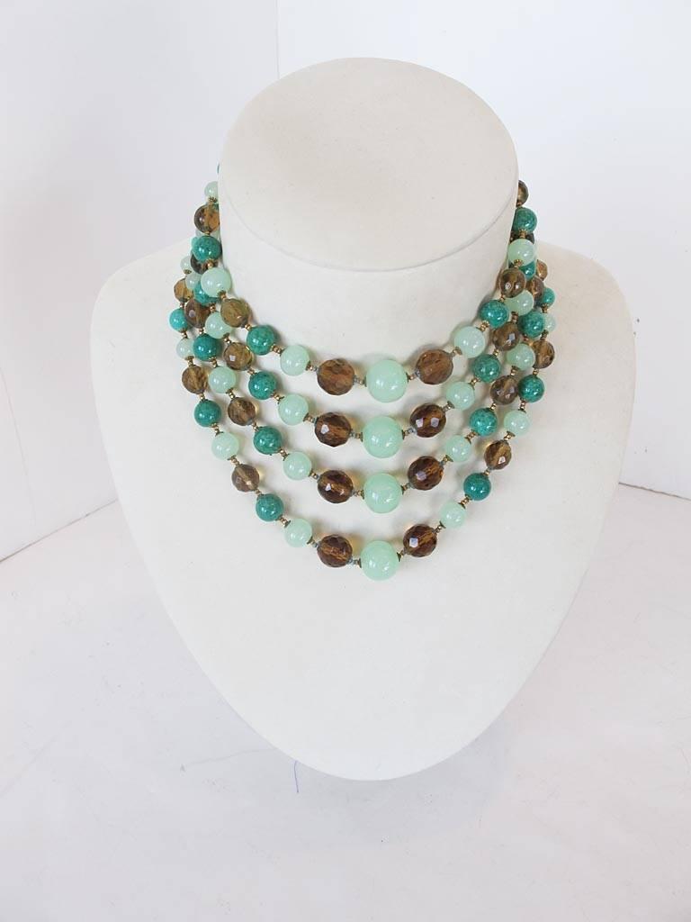 This 1950's Miriam Haskell four strand necklace is made up of three shades of smooth and faceted green glass beads. The clasp is a gold-tone with a hammered pansy motif. The piece is signed.

YOUR PURCHASE BENEFITS THOSE WHO ARE DEVELOPMENTALLY
