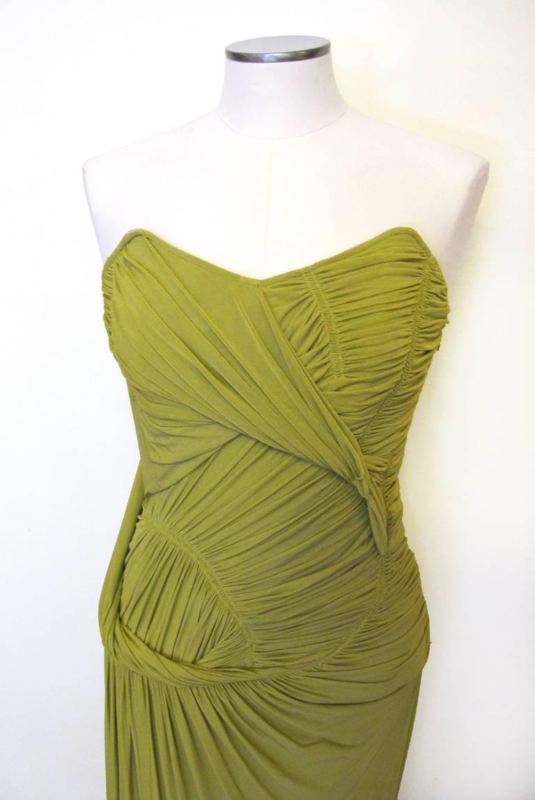 This Donna Karan citrus green matte crepe evening gown is strapless and in a Grecian goddess style. The dress has a built in corset and slits high up the right side of the skirt. The bodice is ruched and draped. The matte crepe fabric is stretch and