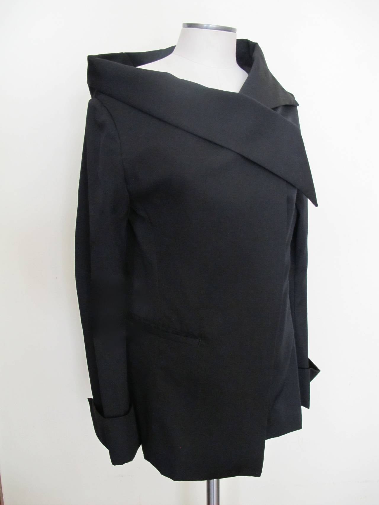 It has the unique touch of one pocket on the right. The shoulder is slanted on the right and the other is a drop shoulder. The jacket is open and flows elegantly on the body. One shoulder falls down and the other shoulder is upright. Sleeve length