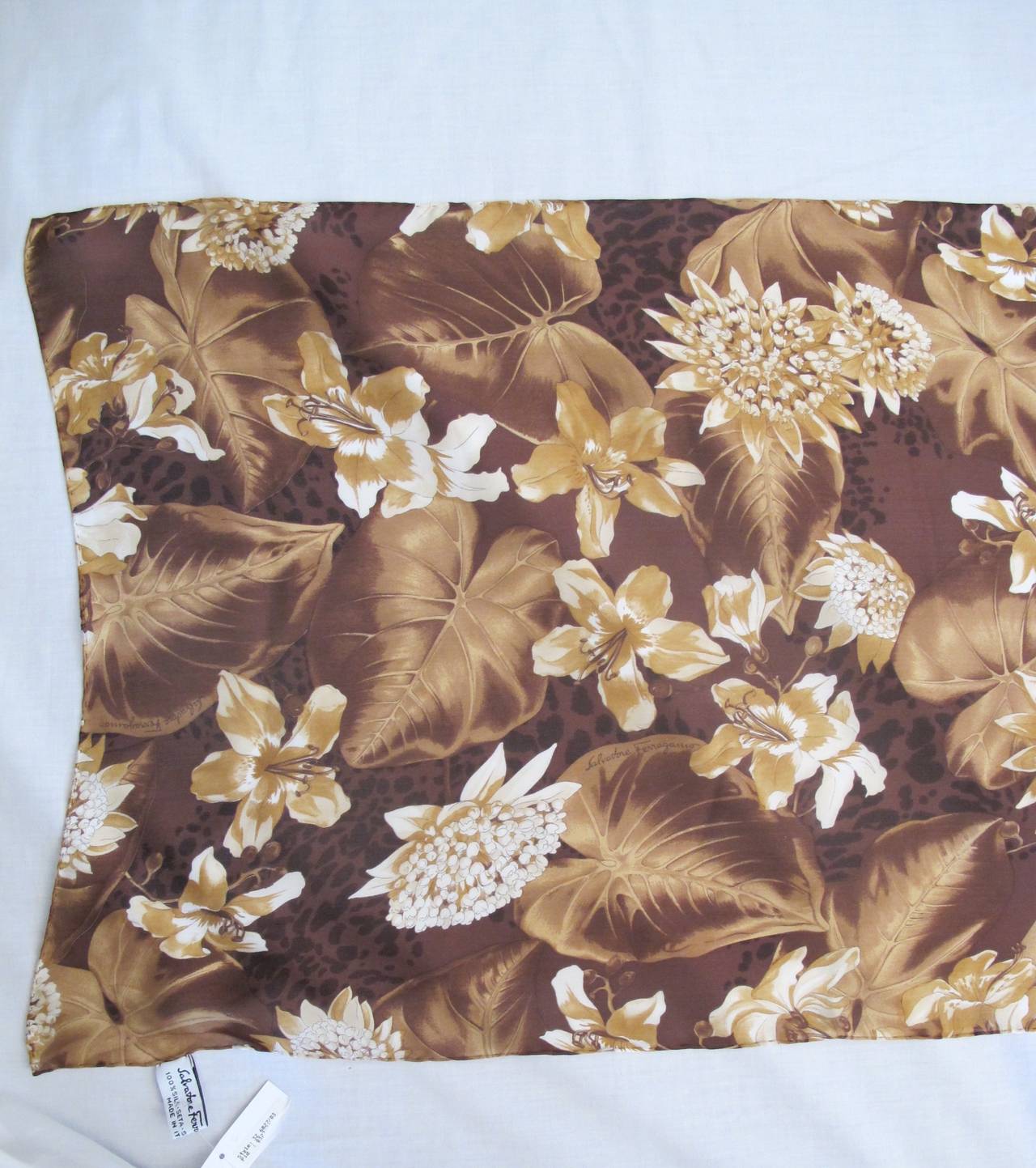 This beautiful scarf is designed with a variety of flowers and leaves with a rich brown background enhanced by different shades of mushroom browns throughout the scarf. The hem is hand-rolled.