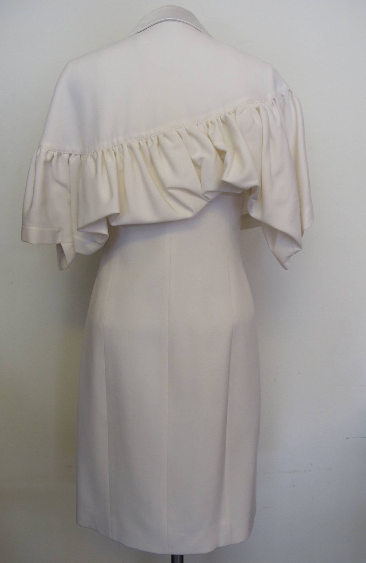 Cape with satin lapels attached to sleeveless dress. Cape is asymmetrical with left side longer and there are two pockets on the dress. Cape is highlighted by gathering. Made approximately 2012-2013. Shoulder to shoulder 14.5 inches.