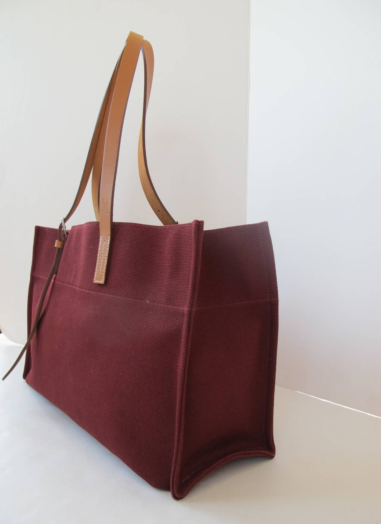 This chic useful Etriviere tote bag with adjustment calfskin handles may be used for every day and travel. It is comfortable to use since it is so light in weight. On the leather handle, it reads: Hermes, Paris, Made in France. The canvas fabric is