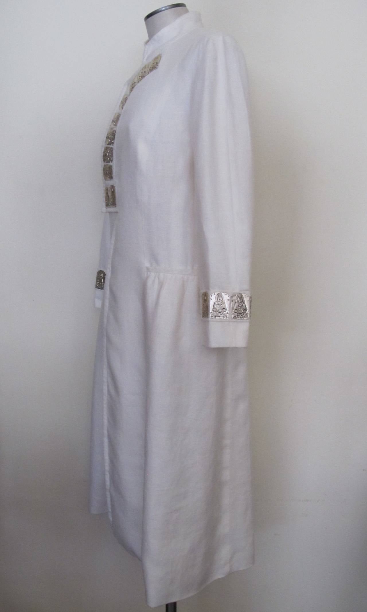 This impressive Vivienne Tam piece was donated to Helpers by the Fashion Director of Saks Fifth Avenue. It was an important piece in her collection. She was a member of the Buddhist Church. The mandarin collar white linen dress has 10 Buddha