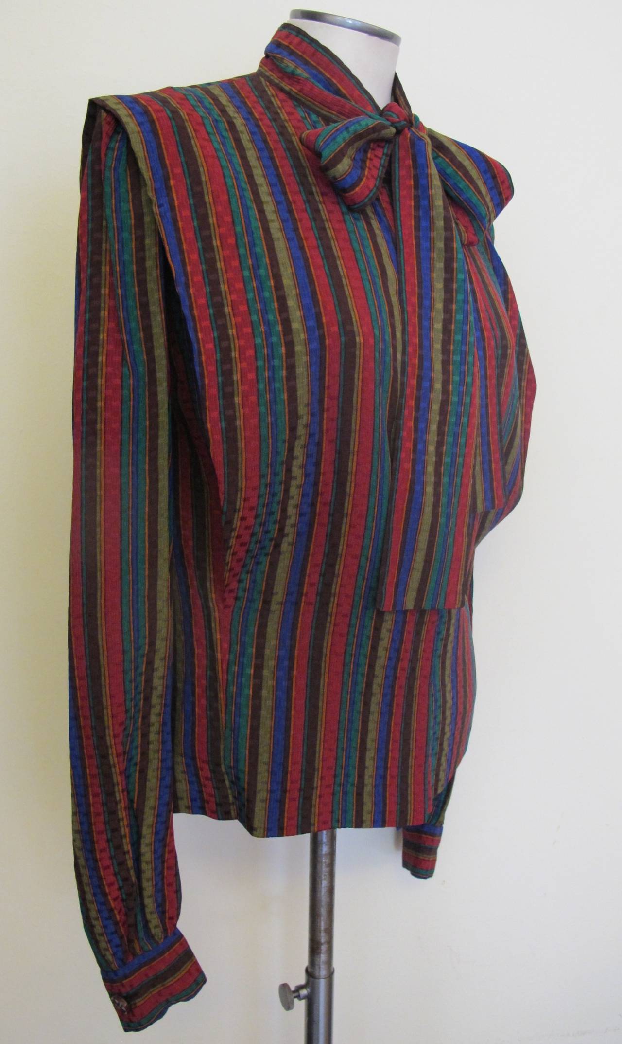 This elegant Boutique Givenchy Blouse is multi-colored stripes: brown, emerald green, maroon, royal blue and olive. Fits size 12-14 (US). Sleeve length measures 26 inches. Shoulder to shoulder measures 16.5 inches.
