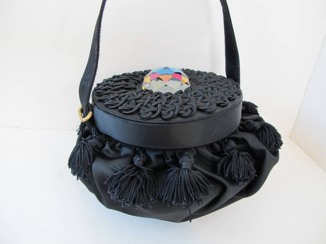 Renaud Pellegrino round black satin evening bag with 12 tassels surrounding it. There is a beautifully executed satin trim design which covers the lid of the 