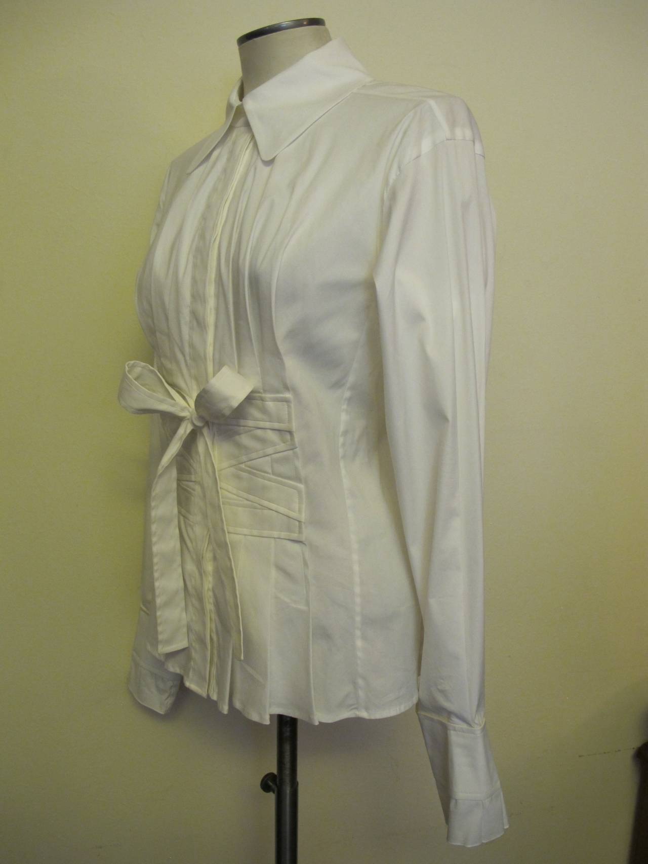 This blouse served as editorial for the YSL House. The material stretches. There is a criss cross and a bow design on the waist with pleats at the bottom of the blouse. There are pleats at the bottom of the cuff. Sleeve Length measures 25 inches.