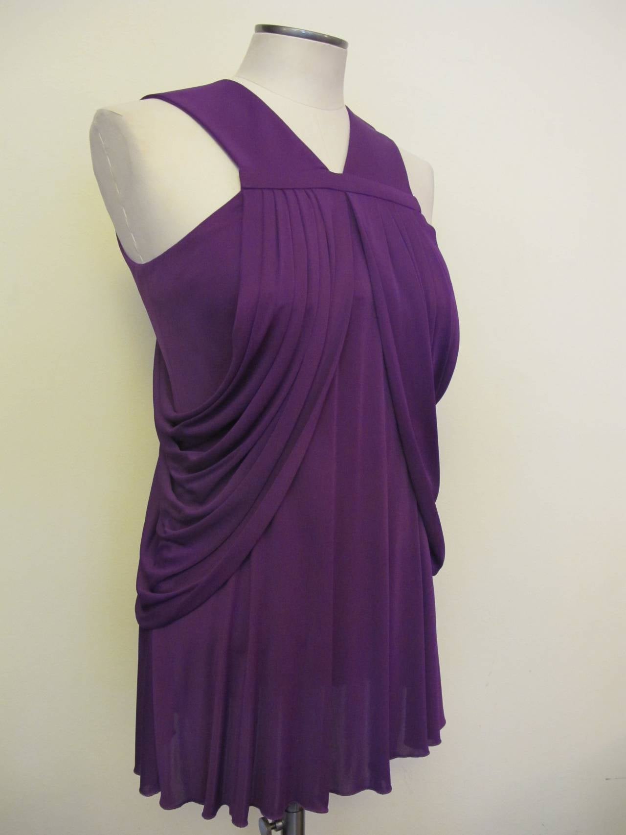 Bight purple Versace sleeveless blouse with pleating on the front shoulders, draping throughout and key hole opening at back with button closure at nape of neck. Fabric stretches. Regular price was $1,395.00. Helpers Price $465.00.
Bust stretches