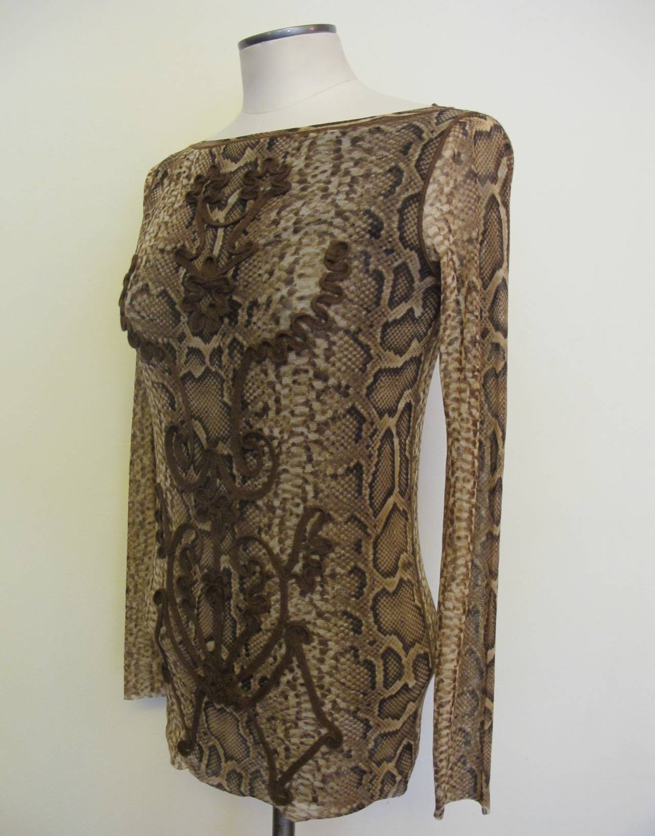 The brown. beige snakeskin blouse has polyester shoe lace trim design from neck to bottom of blouse. There is a 1.5 inch chocolate trim at bottom of blouse. Sleeve length measures 24 inches.