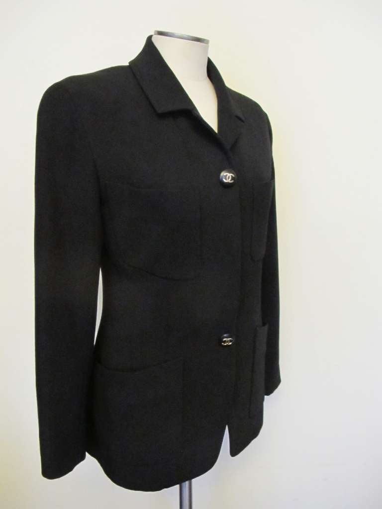 Elegant, iconic, black fine twill wool jacket with 4 buttons - 2 hidden in panel and 2 outside of jacket. Multi-purpose jacket to be used for day and evening. Shoulder to shoulder measures 17.5 inches. Sleeve length measures 23 inches.