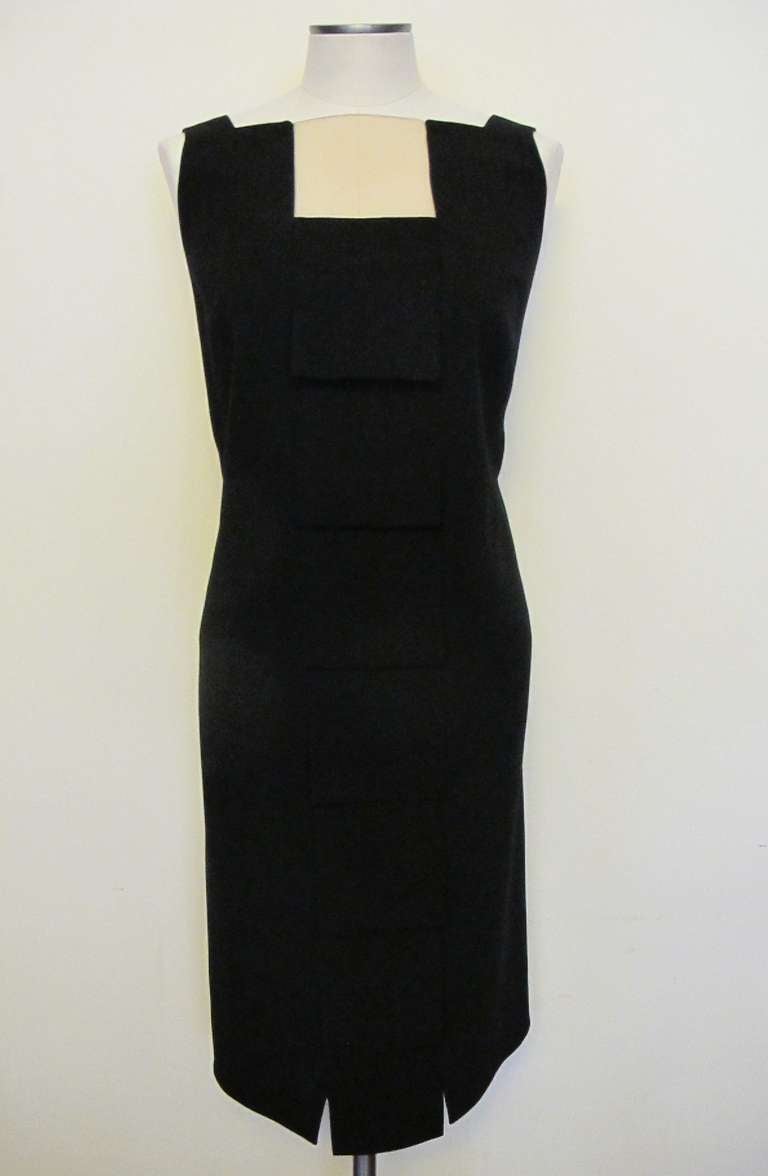 Sleeveless black dress with 7 moveable panel, square flats beginning panel measures 4.5 inches by 4.75 inches and the cascades gradually to last flap which measures 5.75 by 4.75 inches. A natural skin-tone insert at top of dress measures 4.5 inches