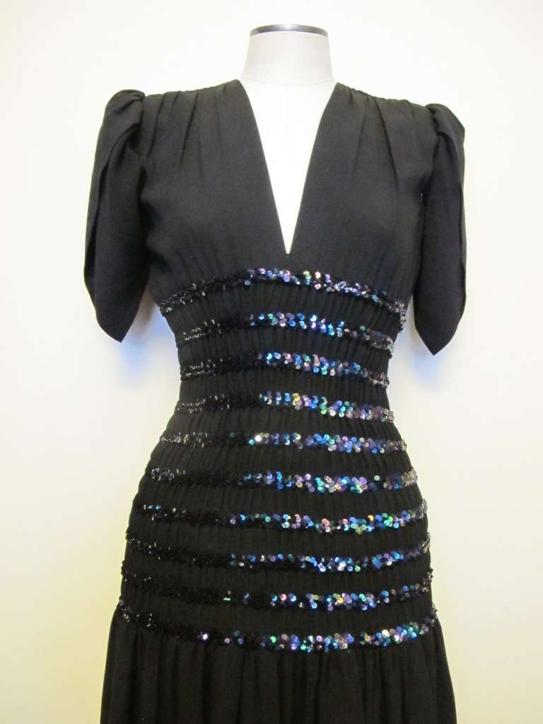 Stunning Yves St. Laurent Cocktail Smocking Dress. There is a 14.5 inch elastic smocking detail, enhanced by 5/8 iridescent strips of black sequins. The tulip short sleeves contribute to the chic look. The smocking elastic detail hugs the figure,