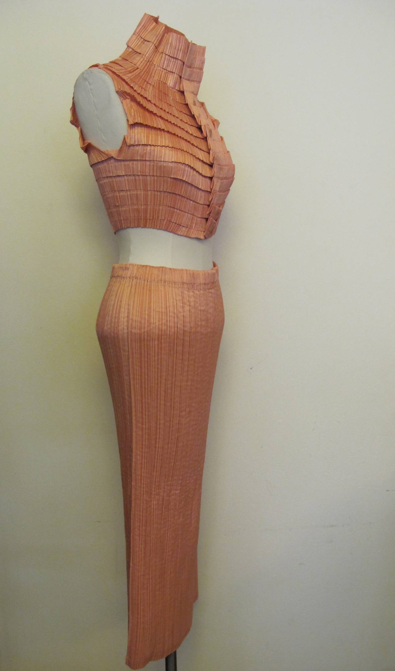 Iconic, lush Issey Miyake light Salmon Blouse and Skirt with great deal of stretch.

Blouse: Shoulder to shoulder measures 12.5 inches. Blouse length measures 17 inches long.

Skirt: Waist measures 26 inches (stretch fabric). Skirt length