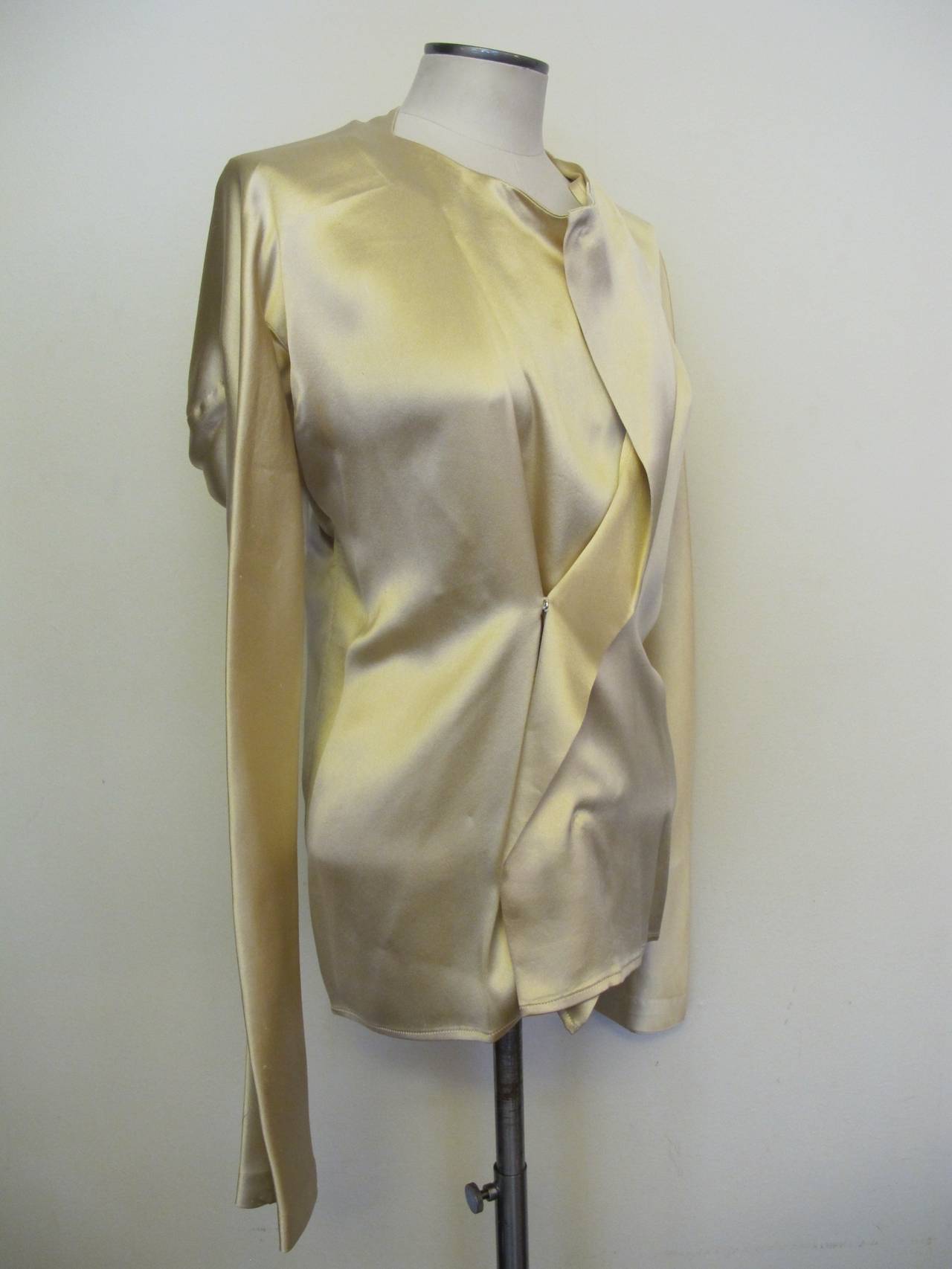 This is an extraordinary impressive silk satin blouse from the collection of the former fashion director of Saks Fifth Avenue. It has a continuous sleeve measuring 72 inches total for both sleeves. The front of the blouse is opened and the top is