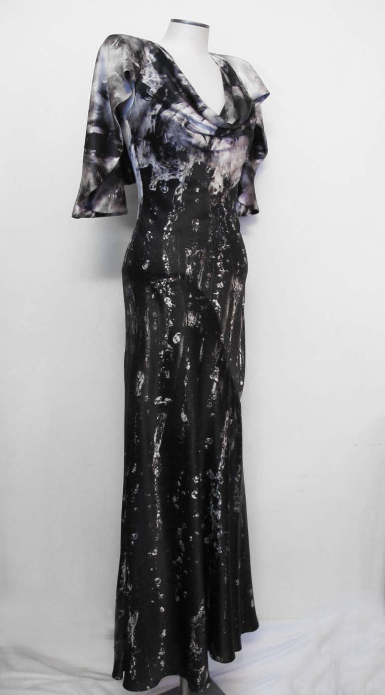 Alexander McQueen died in 2010. This exquisite gown was created by him while he was alive. 

The colors are black and grey and the different shades cascade into a black design where the observer feels the flow of water on the earth. The bottom of