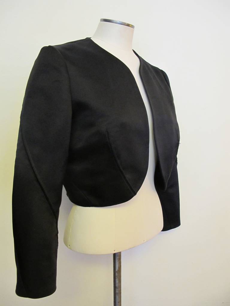 Nina Ricci New Black Satin Bolero Jacket with 2 raw edge seems on the front, back and diagonally on sleeves. This is a perfect addition to a strapless cocktail dress or evening dress. Sleeve length measures 21 inches. Shoulder to shoulder measures