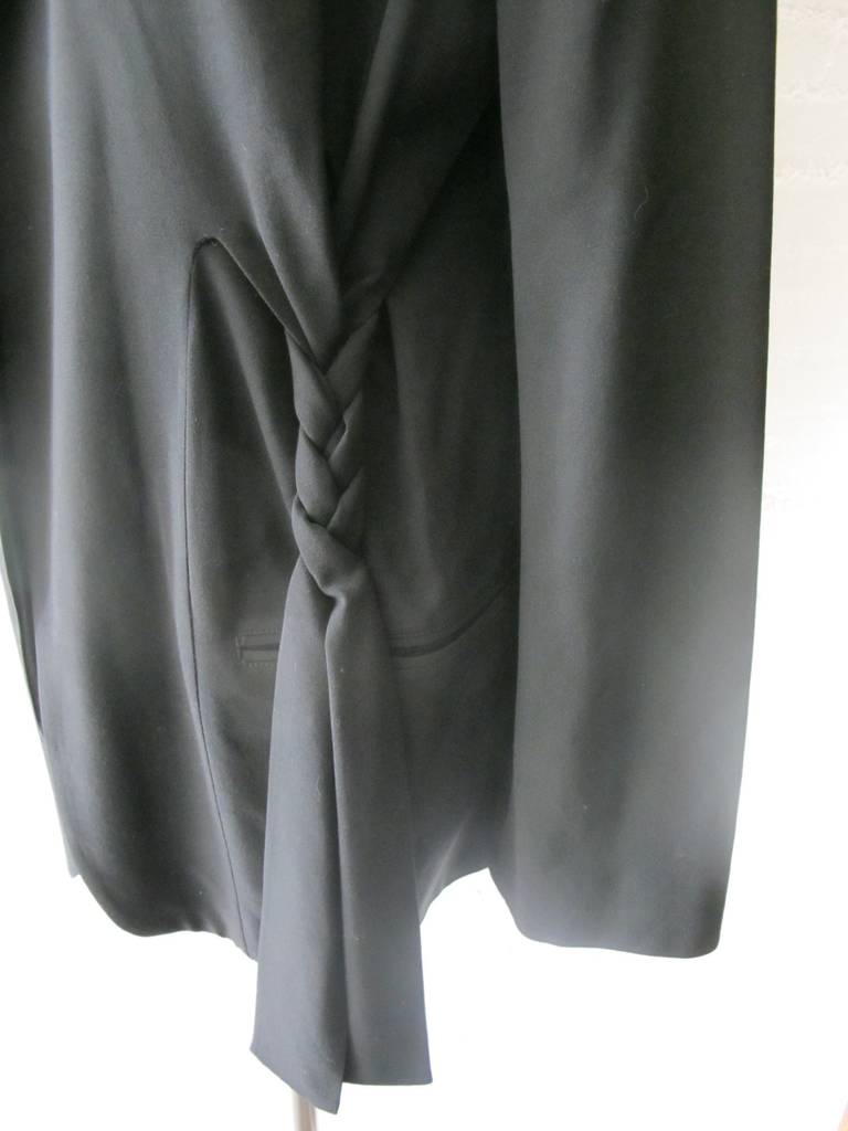 Iconic Yohji Yamamoto open black jacket with braided tie cascading down front of the jacket. The elegant piece is accented by two diagonal pockets. The fabric is exquisite. Sleeve length measure 24 inches. Shoulder to shoulder measures 17.25 inches.