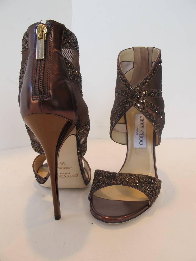 Over-the-top Sandal Evening Bootie with zipper in back of shoe. This shoe is for the collector who is passionate about shoes. Glitter and mesh adorn the chic sandal. The new pair of shoes has a sticker saying Saks Fifth Avenue. The Bronze heel is