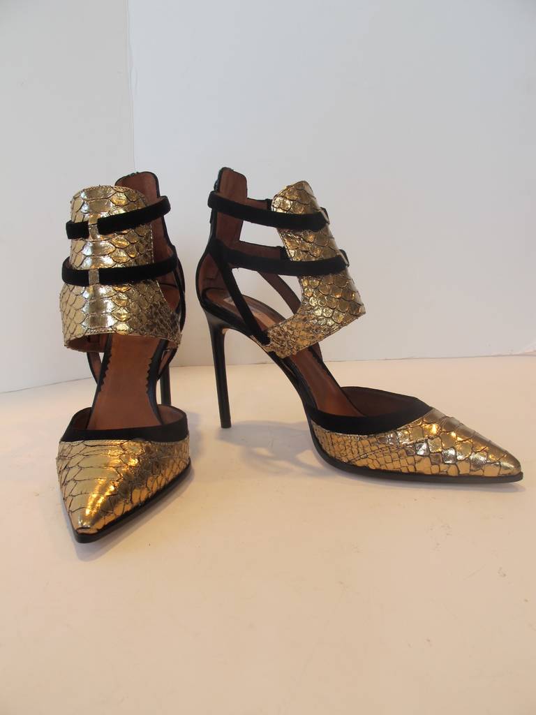 Fabulous over-the-top Reed Krakoff gold snakeskin and black suede harness ankle pumps. Heels are 4 inches high. Buckles catch the two suede straps and there is a zipper which unzips the black leather in back of shoe. Leather wraps around the entire