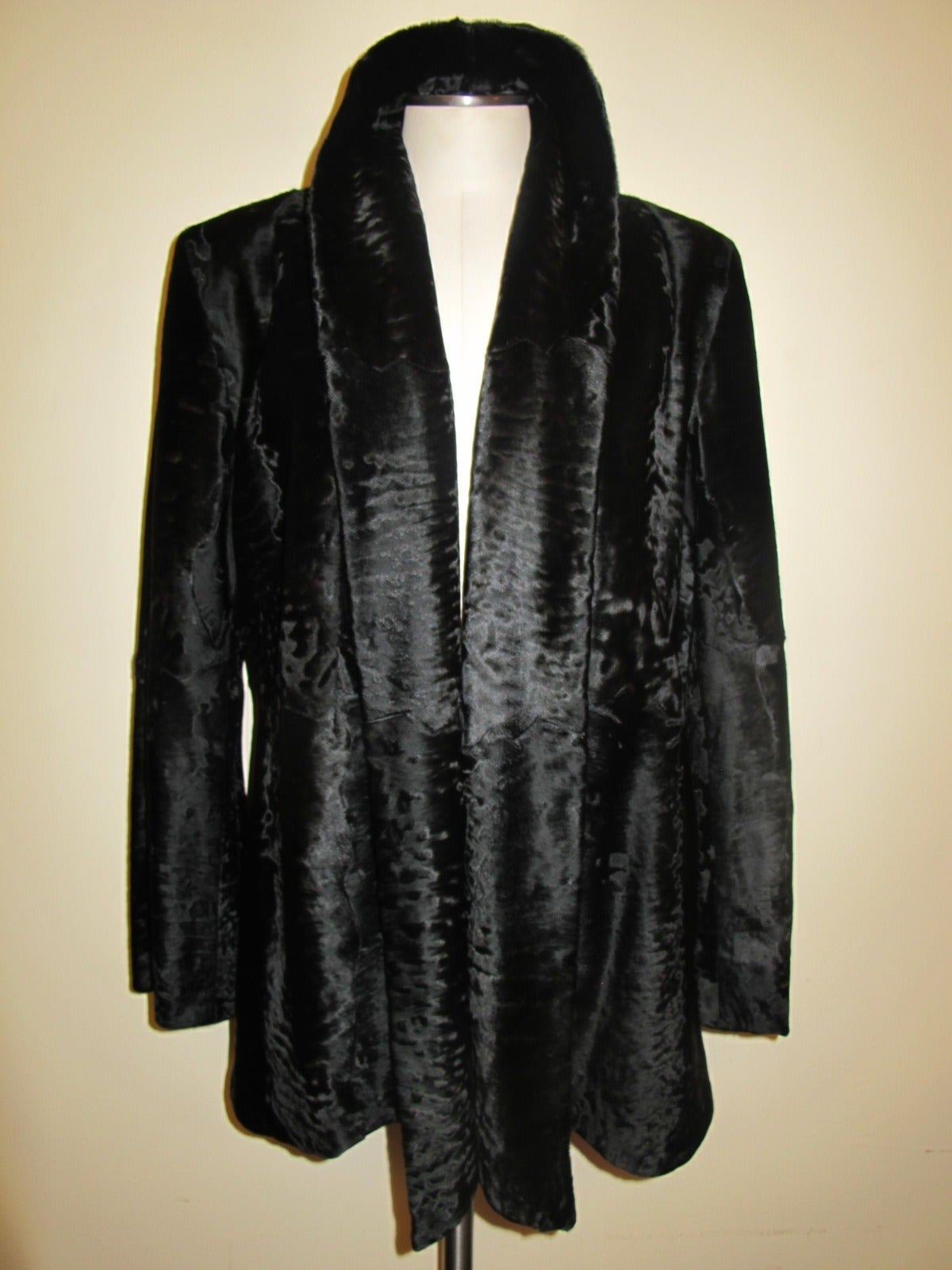 This elegant Giuliana Teso Black broadtail piece is an open jacket. Collar may be worn tuxedo style or standing up. The three inch continuous collar gives a smoking jacket effect. The collar ends in a pointed, angular design. Sleeve length measures