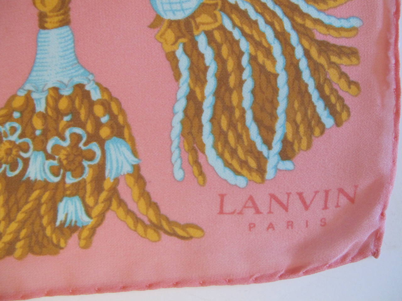 1960's Vintage Lanvin Scarf with Designs of original Lanvin Perfume Bottle with tassels. Important Provenance  (Please telephone us for more information). Hand-Rolled hem. Colors: Cognac, bubble gum pink, sky blue, silver grey.