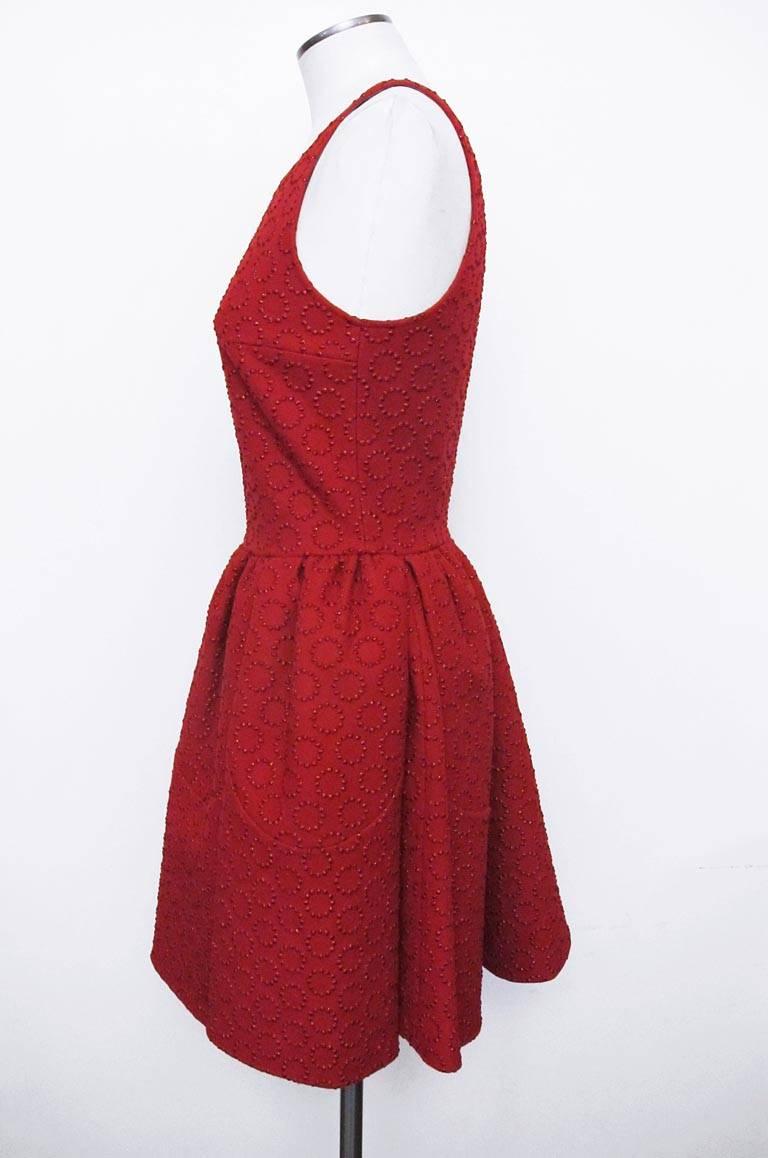This incredibly designed red sleeveless dress has petal shaped insets in the full skirt. The dress features a circular three-dimensional metallic pattern throughout. 

Still attached is the original price with original tag: $6,675.00

Shoulder