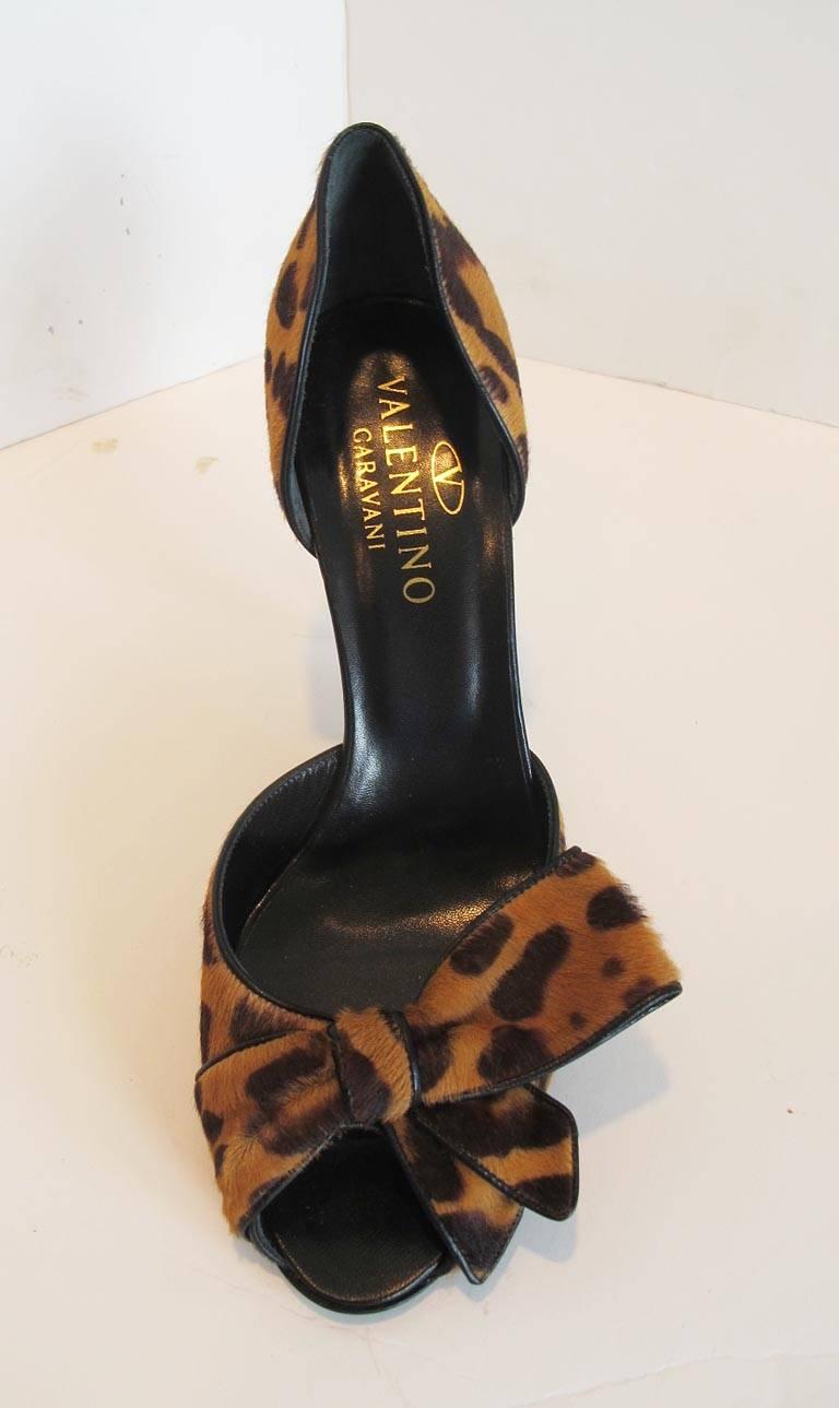 These exquisite open toe leopard print pony hair shoes are enhanced by an exaggerated bow,black leather piping and black 4