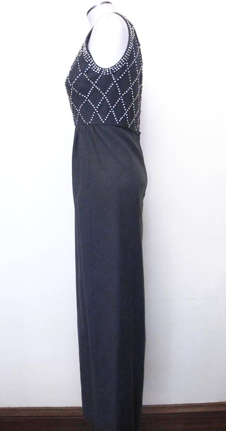 This chic 1960's sleeveless grey flannel evening gown with rhinestone incrusted bodice has two 6.5' slits on each side of the bottom of the skirt.