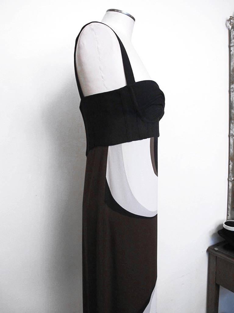 Vogue referred to the print of this exciting Versace 1960's inspired gown as an abstract design. The gown has a geometric swirl print with a fitted corset bodice. It is empire style with no waist. The colors of the piece are black, brown, light grey