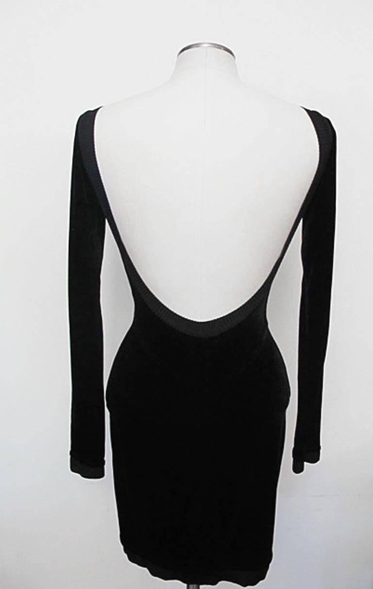 This chic black velour Alaïa dress has long sleeves, a low scooped neckline and exaggerated low back. There is a .75 inch knit black band around the neck and sleeves and a 1.5 inch knit band at the hem of the dress. Shoulder to shoulder 14