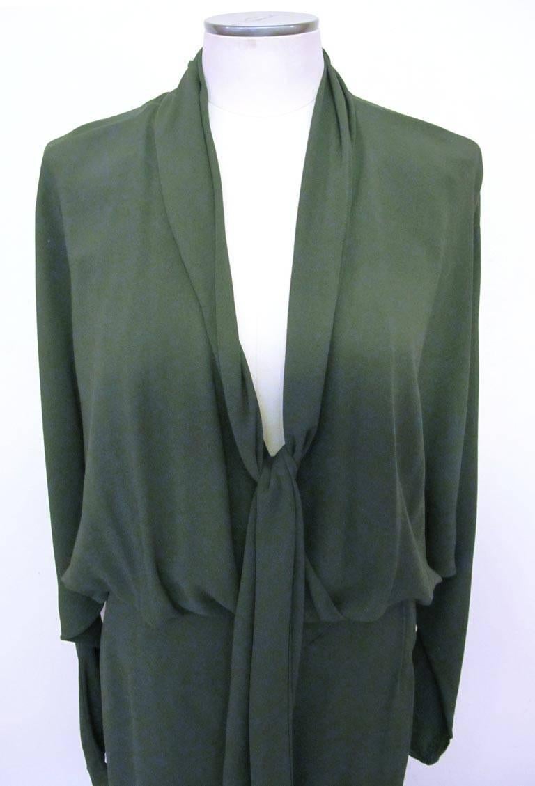 This exquisite Halston avocado green jumpsuit has two pockets , a deep plunging neckline and dolman sleeves. The banded waist is gathered. A matching 7 x 130 inch long scarf that is cut on the bias accompanies the piece. The jumpsuit is 100% silk