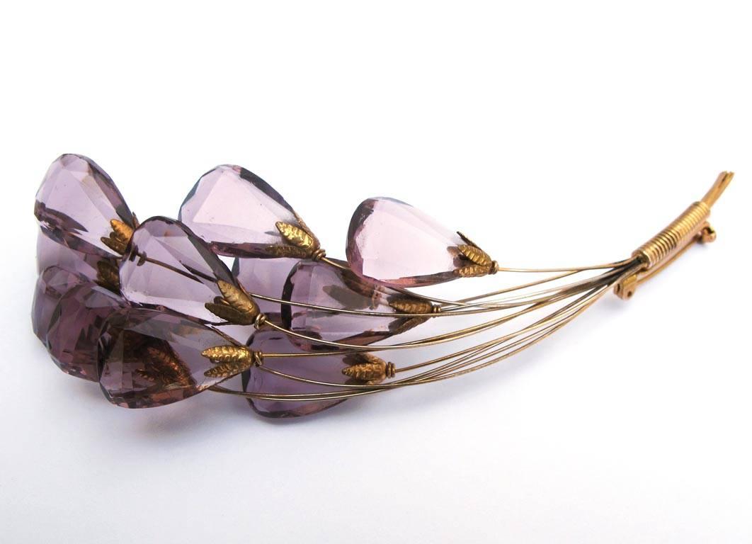 This fabulous 1940's brooch has a bouquet of flowers design. The faceted glass stones are amethyst colored and the setting is a gold-tone. Since each stem is separate there is a great movement to the piece.

YOUR PURCHASE BENEFITS THOSE WHO ARE