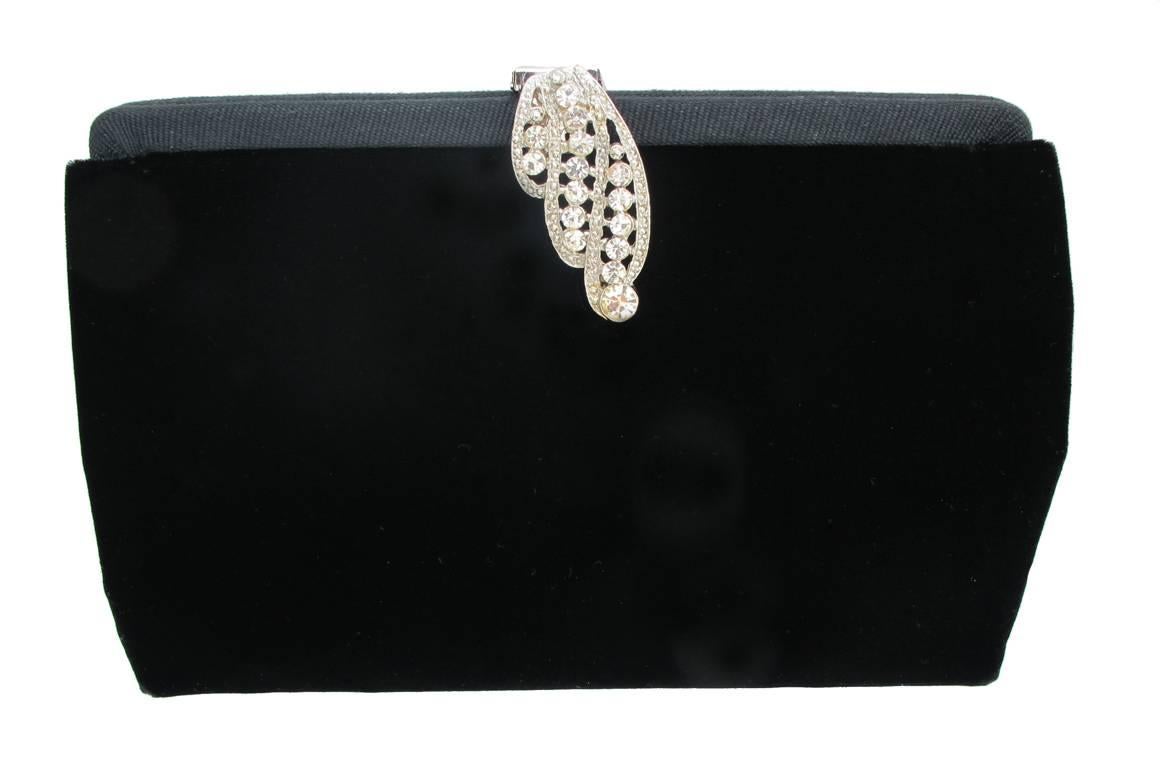 This beautiful 1990's black velvet Givenchy clutch has a decorative rhinestone clasp.There is a hidden silver-tone chain inside that extends out to convert the clutch into a shoulder bag. Inside the bag there are two pockets and one is zippered. The