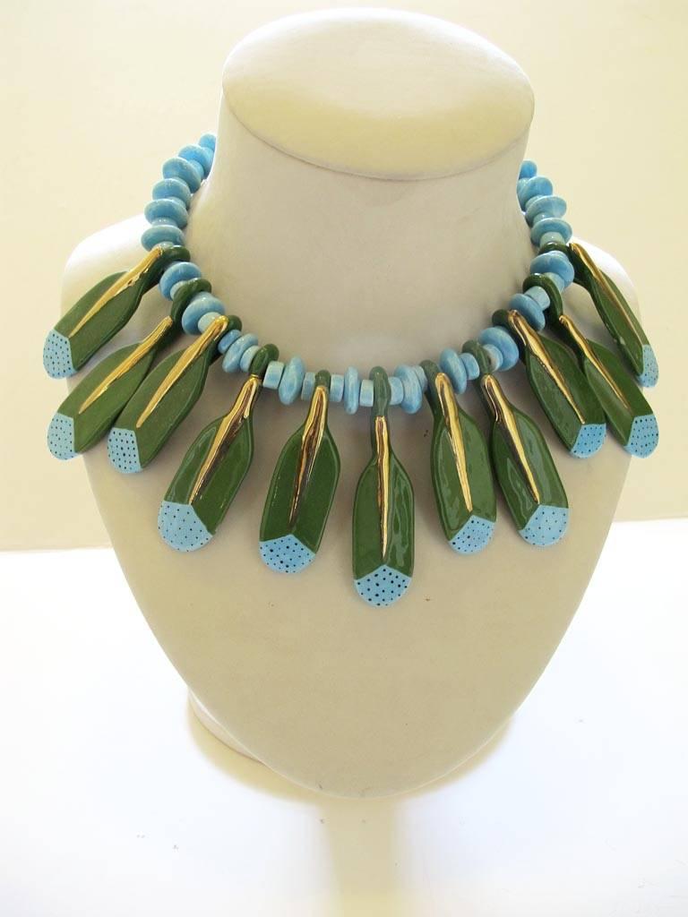 This vintage 1970's Parrot Pearls metallic gold, turquoise blue and forest green ceramic beaded choker necklace has a feather motif and is signed. Parrot Pearls was founded in 1975 in San Francisco and was known for it whimsical handmade ceramic