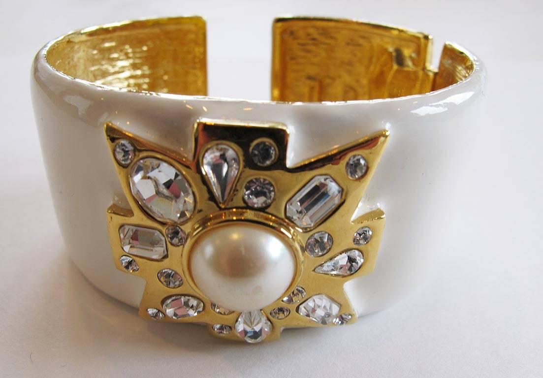 Kenneth Jay Lane Maltese cross cuff bracelet in white enamel and gold-tone with rhinestones and faux pearl. Spring opening for easy on and off. Signed.

YOUR PURCHASE BENEFITS THOSE WHO ARE DEVELOPMENTALLY DISABLED.