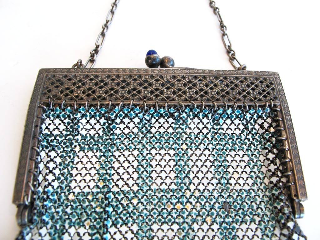 Vintage 1920's off-white and teal enameled mesh purse in plaid. Silver-tone pierced frame with latticework cut-out pattern and flower detail. Cobalt blue glass bead clasp. Seven point Van Dyke fringe hem.

YOUR PURCHASE BENEFITS THOSE WHO ARE