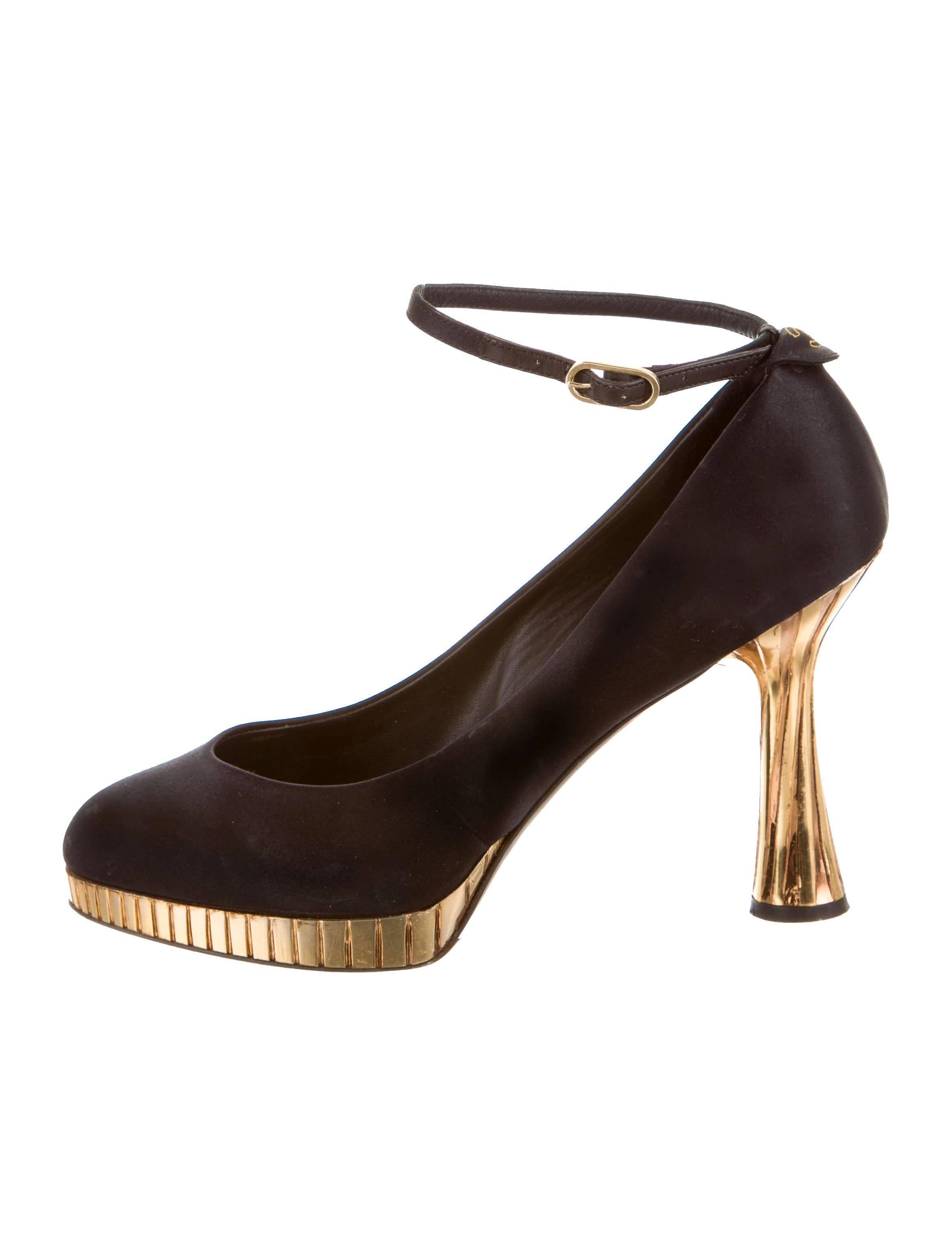Sample Item. Black satin Chanel platform pumps with round toes, interlocking CC embroidery accents at counters, metallic sculptured heels and gold-tone buckle closures at ankle straps.

Measurements: Heels 4.25