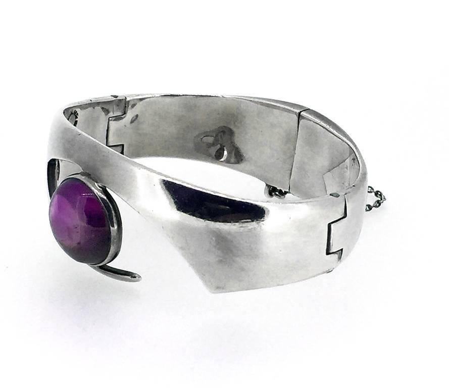 This Taxco vintage sterling silver cuff bracelet has an amethyst cabochon within the eye design. Signed by Sigi Pineda. Created in 1940's. Made in Mexico.
The modernist design is bold and beautiful. The piece has a hinged opening with a safety
