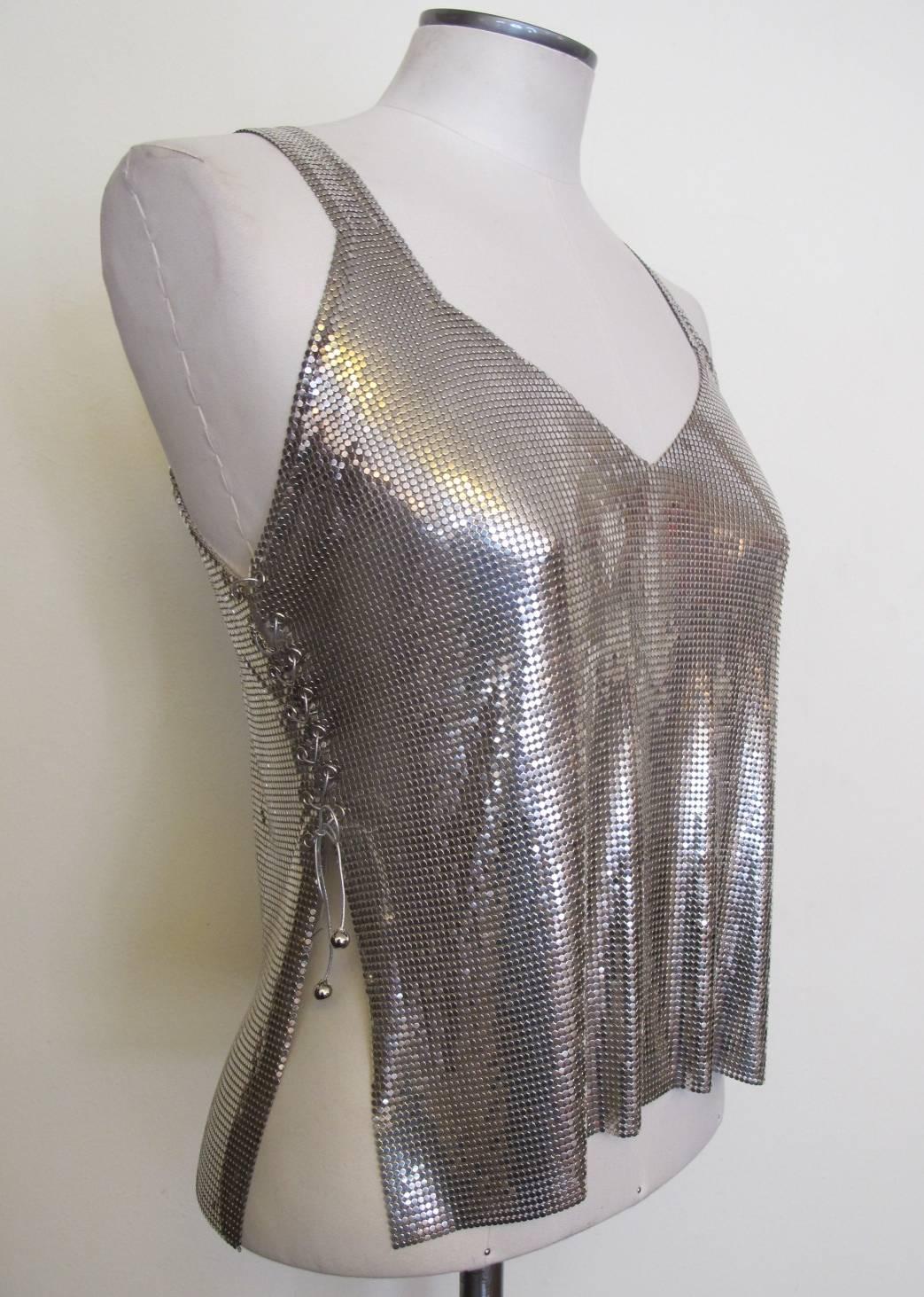 This over-the-top silver metal tank top is perfect for day or evening. There is an oval metal label inside the tank top saying: Paco Rabanne. Robanne through the decades has used the metal mesh medium for some of his impressive pieces. The sides are