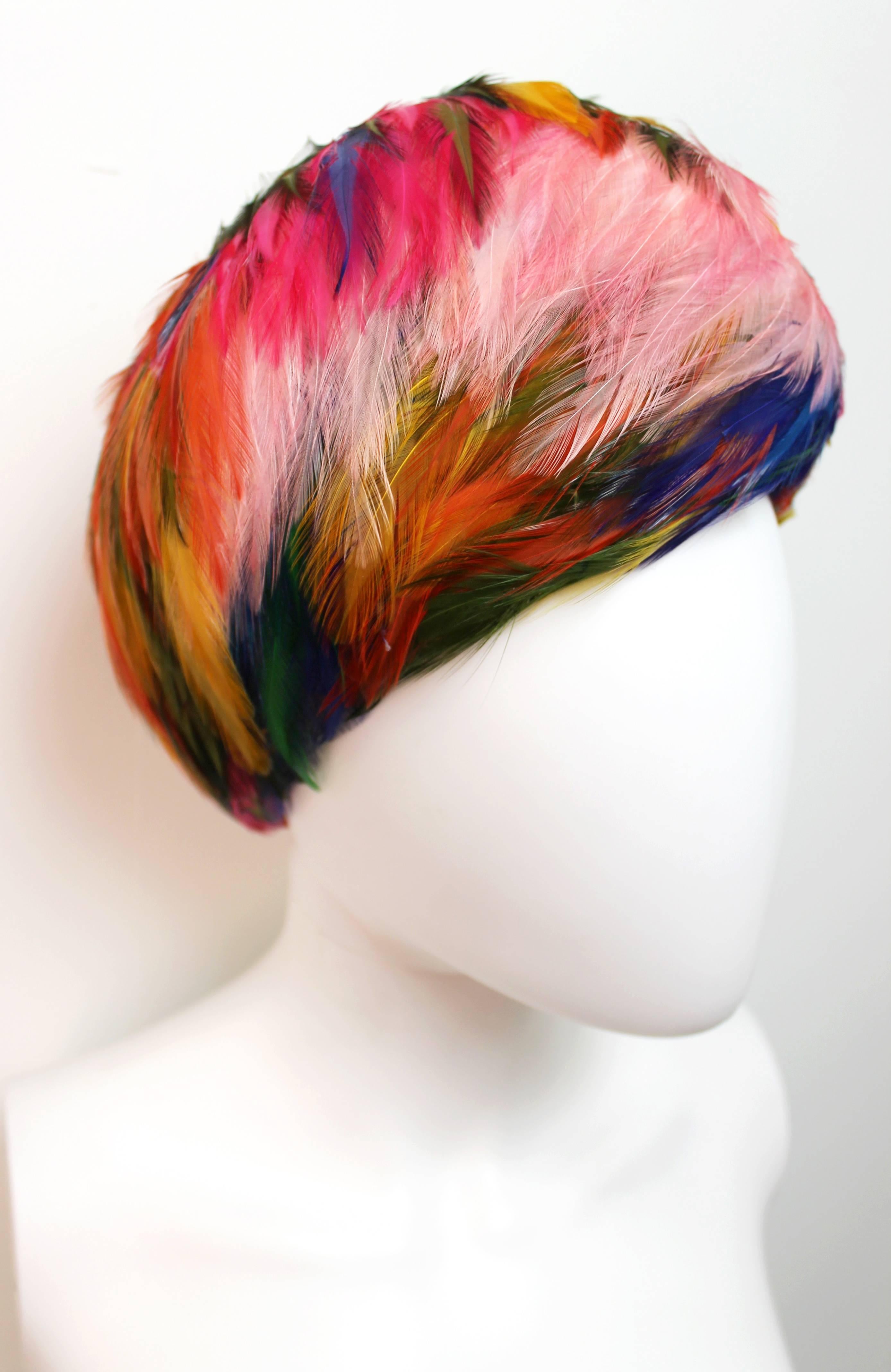 Beautiful hat by Christian Dior from 1960. Features vibrantly colored feathers that form a rounded shape around the head. Comes with the original box.