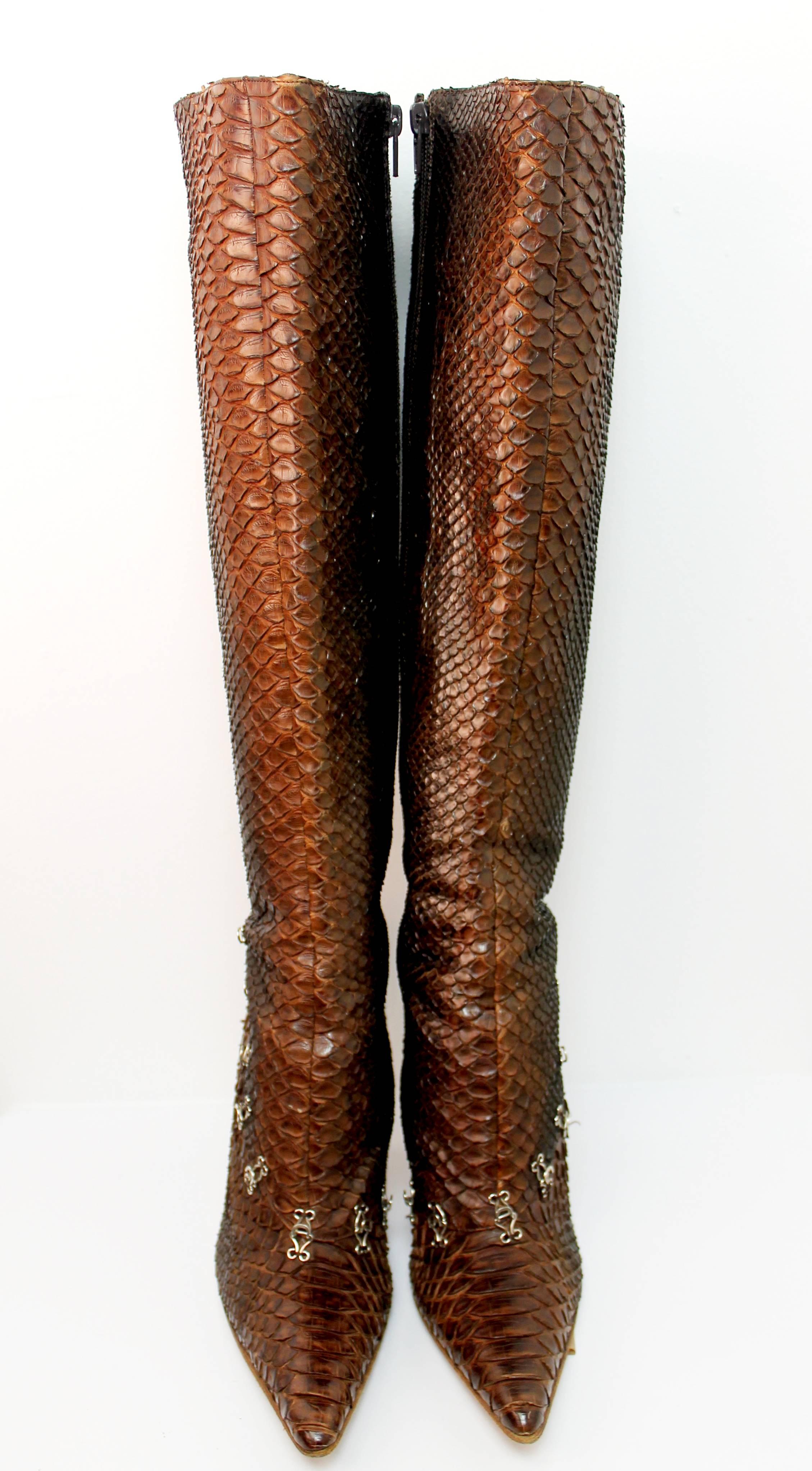 Stunning brown python knee-high pointed toe boots from John Galliano's Autumn/Winter 2001 collection. Features small silver hook and eye buckles from the middle of the foot to the top of the calf. 