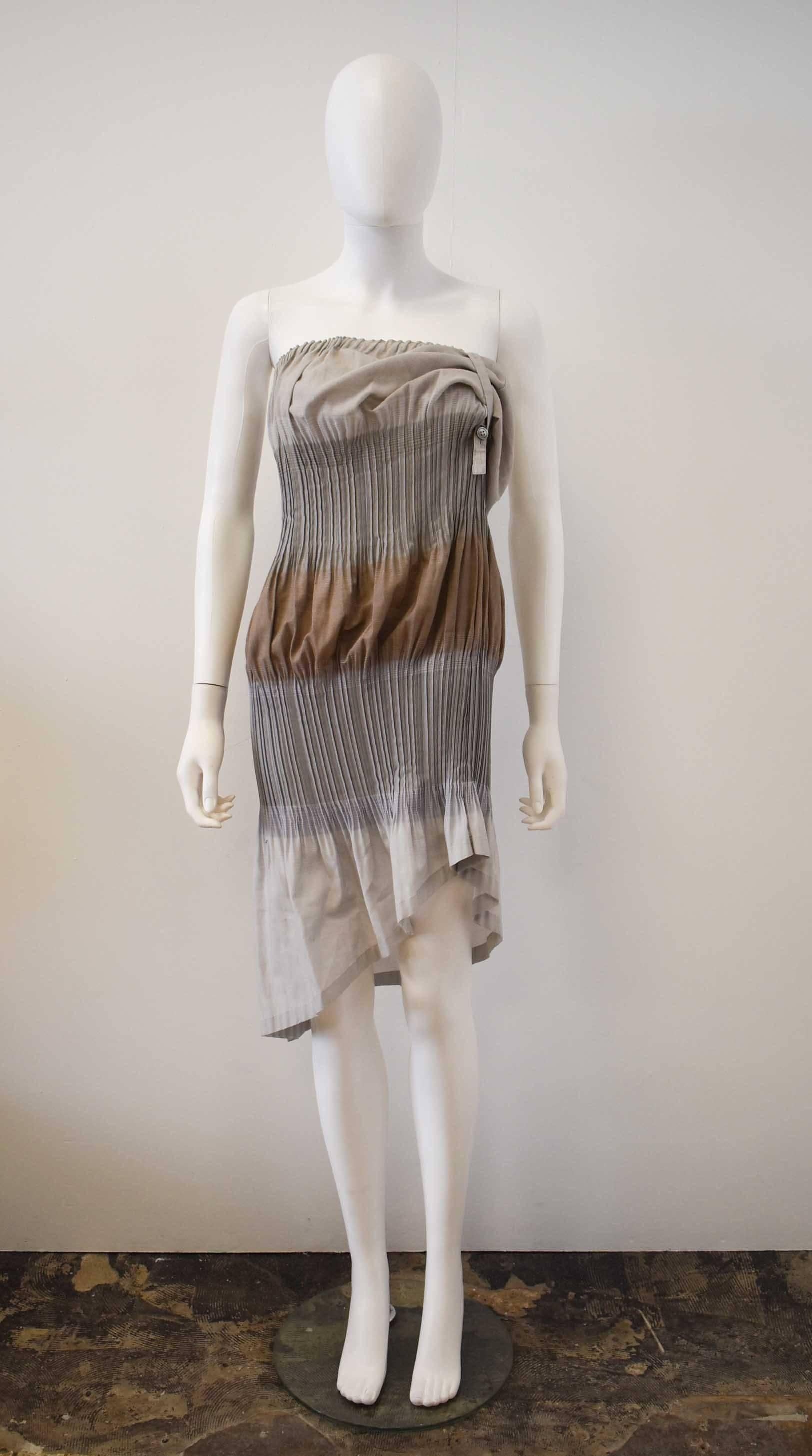 A quirky and unusual dress by innovative Japanese brand Issey Miyake. The dress has an elasticated waist and a subtle horizontally striped pattern to the fabric, creating bands of colour from grey to brown. Following this banded colour pattern, the