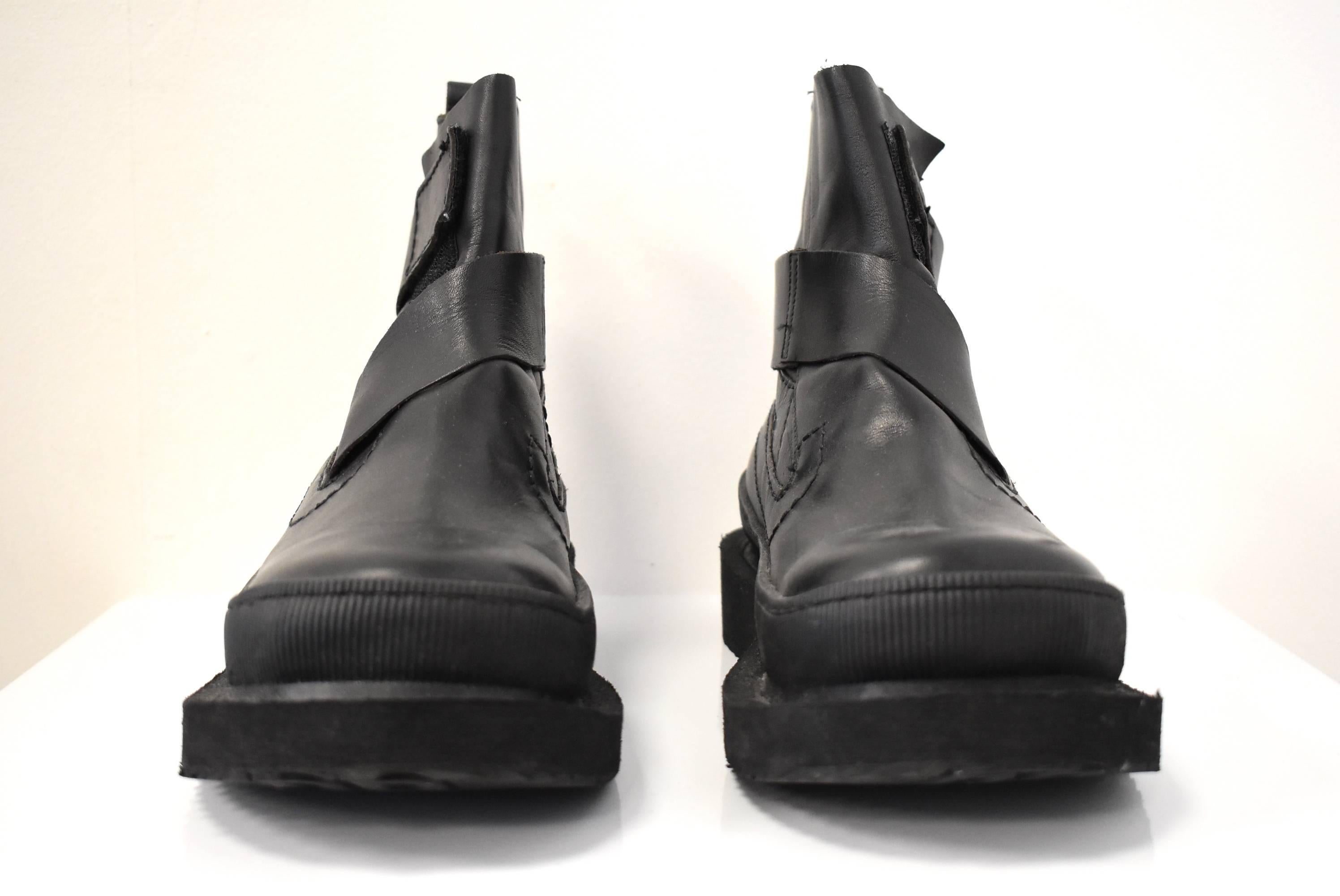 A pair of virtually unworn black leather pull-on boots by Dirk Bikkembergs. The boots have a wrap-around strap that velcros at the top of the boot. 
The chunky boots have a slight 1.5 inch heel to give extra height. Despite their thickness, the