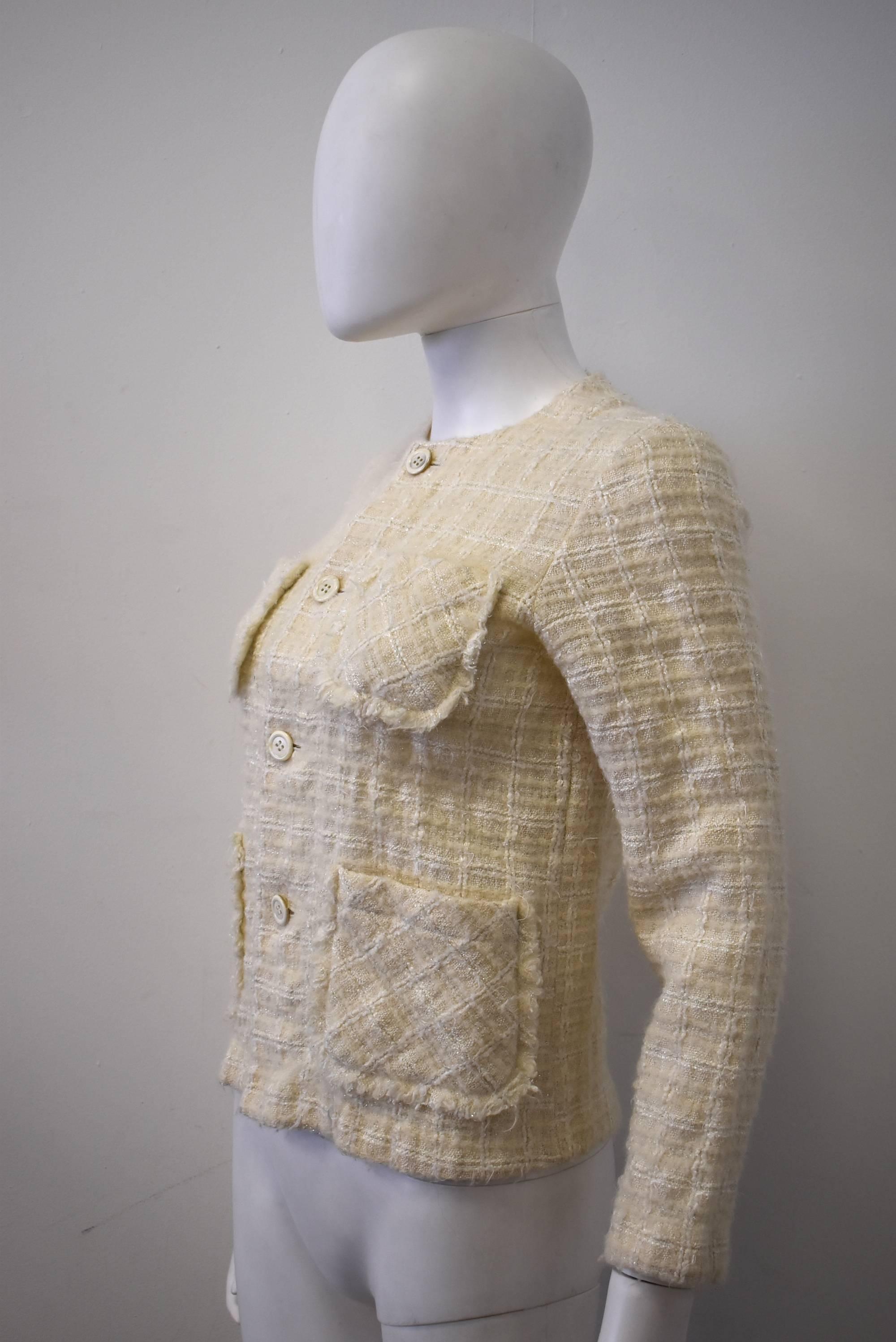 An elegant and classic cream boucle jacket from the Tricot line of Comme des Garcons. The jacket has a cropped, boxy shape that looks toward Chanel's classic jackets as inspiration. There are four patch pockets on the front of the jacket and button